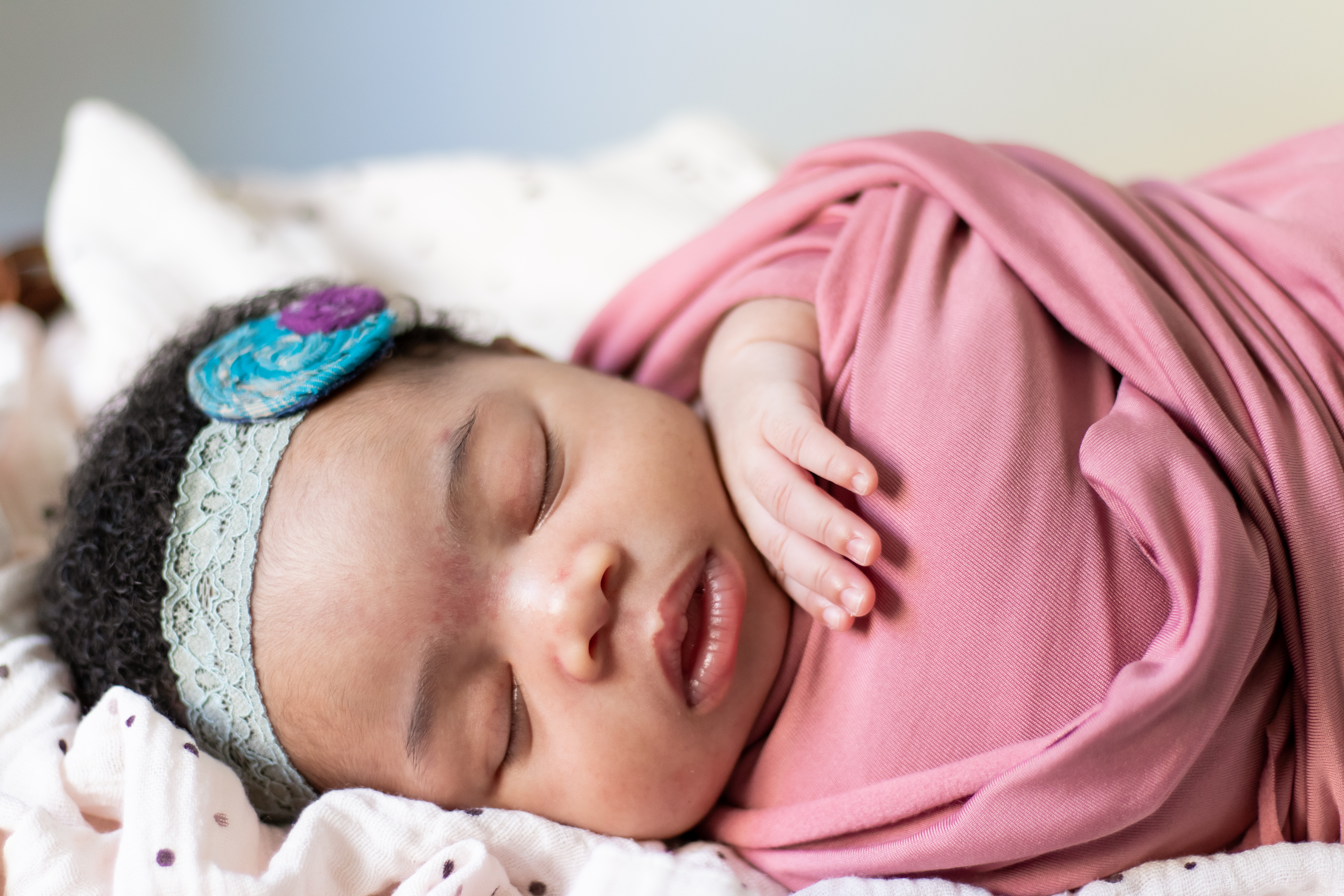 Sleeping newborn swaddled in pink wrap, baby photographer